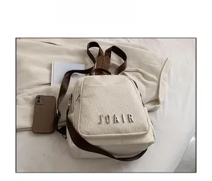 Détail du sac à dos de voyage beige avec logo JOAIR et bretelles en tissu marron
