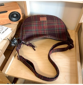 Gros plan du sac demi-lune rétro à carreaux avec logo en cuir et texture en laine