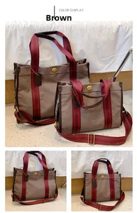 Detail of brown canvas tote bags with striped webbing straps and gold twist lock closure