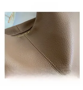 Macro shot of brown pebble grain leather stitching and golden zipper on shoulder bag