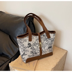 Close-up of vintage floral canvas tote with leather trim and golden twist lock detail