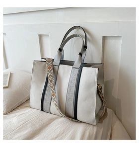 Détail du sac cabas blanc cassé avec large bandoulière jacquard et lettrage de marque embossé