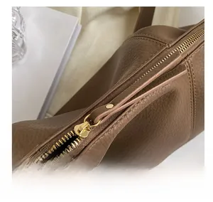 Macro shot of smooth gold-tone zipper on textured brown leather commuter bag