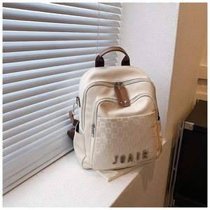 Détail d'un sac à dos blanc cassé avec gaufrage en damier et logo JOAIR métallique