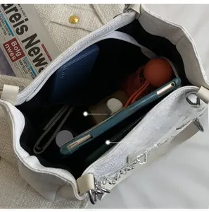 Vue détaillée de l'intérieur d'un grand sac cabas en dentelle blanche avec divers accessoires