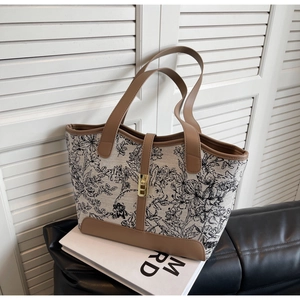 Close-up of canvas tote bag with floral pattern, leather trim and gold twist-lock closure