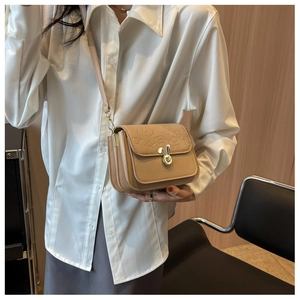 Detail of khaki crossbody bag with golden rabbit twist-lock and embossed motifs