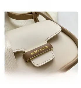 Close-up of minimalist leather bag with golden metal logo and premium stitching