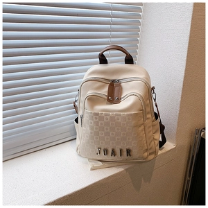 Détail du logo JOAIR et texture grillagée sur un sac à dos de voyage crème