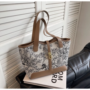 Detail of floral canvas tote bag with brown leather trim and golden metal clasp