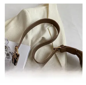 Detail of adjustable brown pebbled leather shoulder strap with golden metal buckle