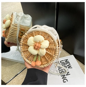 Detail of straw woven round bag featuring fabric flower decor and pearl chain strap
