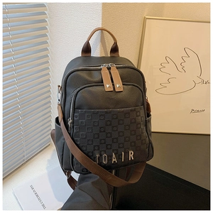 Gros plan du sac à dos en cuir noir avec gaufrage en damier et logo métallique IOAIR