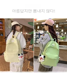 Detail of cream and mint green nylon backpacks featuring cute plush puppy charms