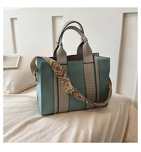 Détail du sac cabas bleu canard avec poignées en cuir gris et bandoulière à motif ethnique