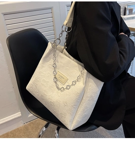 Détail du sac cabas blanc gaufré avec bandoulière fleurie et étiquette de mode