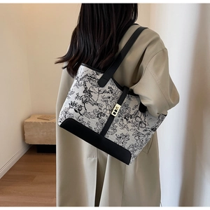 Detail of canvas tote bag with black toile print and elegant leather strap accents