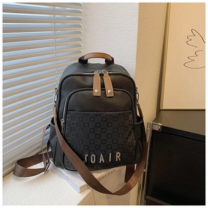 Détail de sac à dos noir grainé avec poche à carreaux et fermetures éclair argentées chic