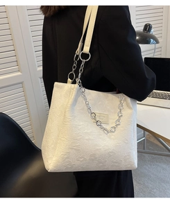 Détail du sac cabas blanc à texture florale avec chaîne argentée et bandoulière