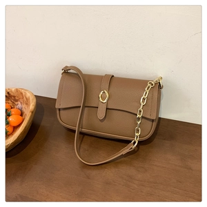 Dettaglio borsa in pelle color caramello con chiusura dorata e tracolla a catena oro