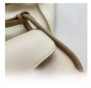 Detail showing high-quality double stitching and leather buckle on contrast color crossbody bag
