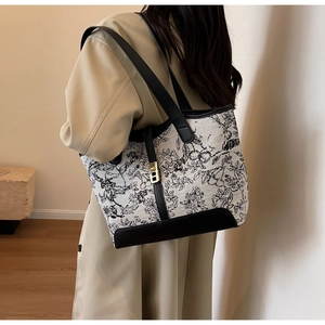 Close-up of floral canvas tote bag showing black leather handles and gold metal clasp