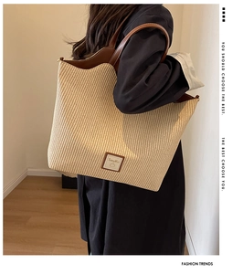 Détail du sac cabas en paille tissée avec bordure en cuir marron et logo SouKu