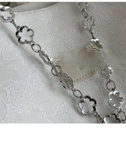 Détail de la bandoulière en métal fleuri argenté et logo en cuir sur le sac