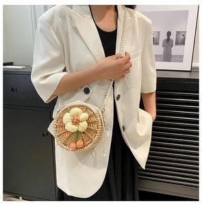 Close-up of hand-woven round straw bag with yellow flower and pearl strap detail