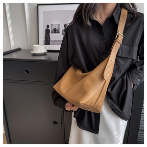 Close-up of caramel leather dumpling bag showing lychee grain texture and wide strap