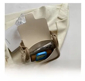 Top-down view showing interior capacity of minimalist white crossbody bag with brown trim