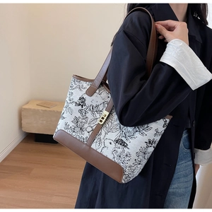 Detail of vintage floral canvas tote bag with brown leather trim and golden metal clasp