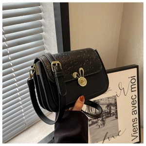 Detail of black leather crossbody bag featuring bunny ear lock and embossed patterns