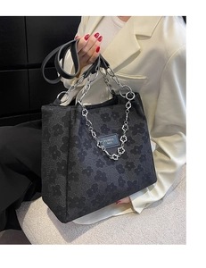 Détail de la texture florale en relief et chaîne argentée sur grand sac cabas noir