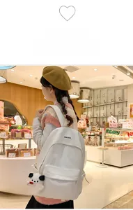 White minimalist backpack with panda charm shown in a cozy bakery environment