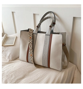 Gros plan du cabas en toile avec lanières en cuir et bandoulière tissée à motifs géométriques