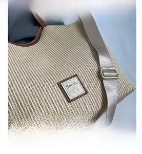 Gros plan du sac cabas tissé avec motifs ondulés beiges et écusson en cuir