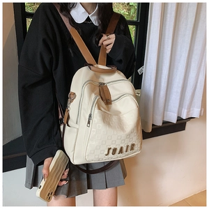 Gros plan d'un sac à dos blanc crème avec motif à carreaux et logo en métal