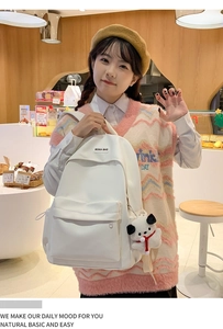 Detailed view of white nylon backpack with square logo and plush dog charm accessory