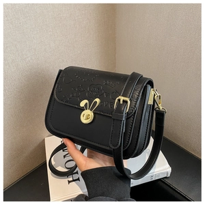 Detail of black crossbody bag with gold bunny lock and cartoon embossed texture