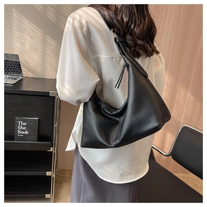 Detail of black pebbled leather texture and slouchy design on a large shoulder tote bag