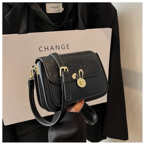 Detail of black crossbody bag featuring a golden rabbit-shaped twist lock and embossed cover