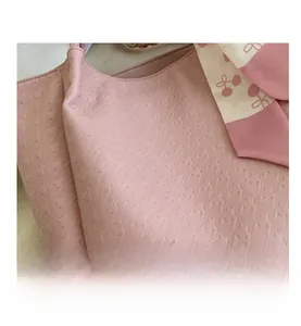 Detail of pink tote bag with star embossed texture and cherry pattern silk scarf handle