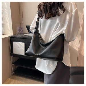 Detail of black pebbled leather tote bag with wide strap and minimalist design