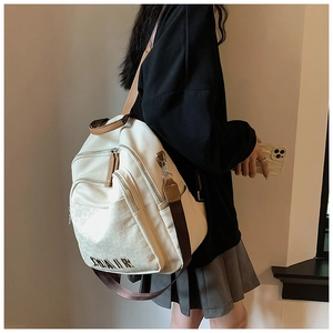 Détail du sac à dos en cuir crème avec bretelles marron et logo en métal doré