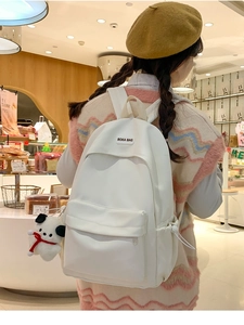 Rear view of a minimalist white nylon backpack for women with a cute panda plush charm