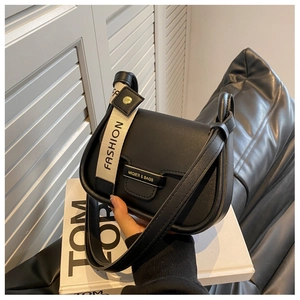 Detail of black faux leather crossbody bag with wide fashion strap and metal buckle