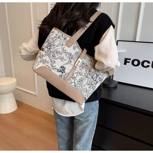 Close-up of floral canvas tote bag with leather trim and decorative metal buckle strap