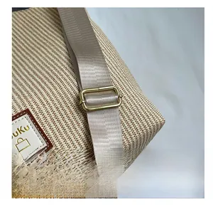 Gros plan du sac cabas tissé avec boucle dorée réglable et détail de bandoulière brune