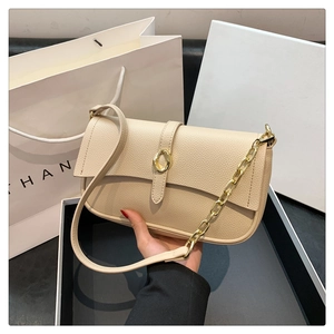 Dettaglio borsa sottobraccio in pelle beige martellata con fibbia oro e catena metallica